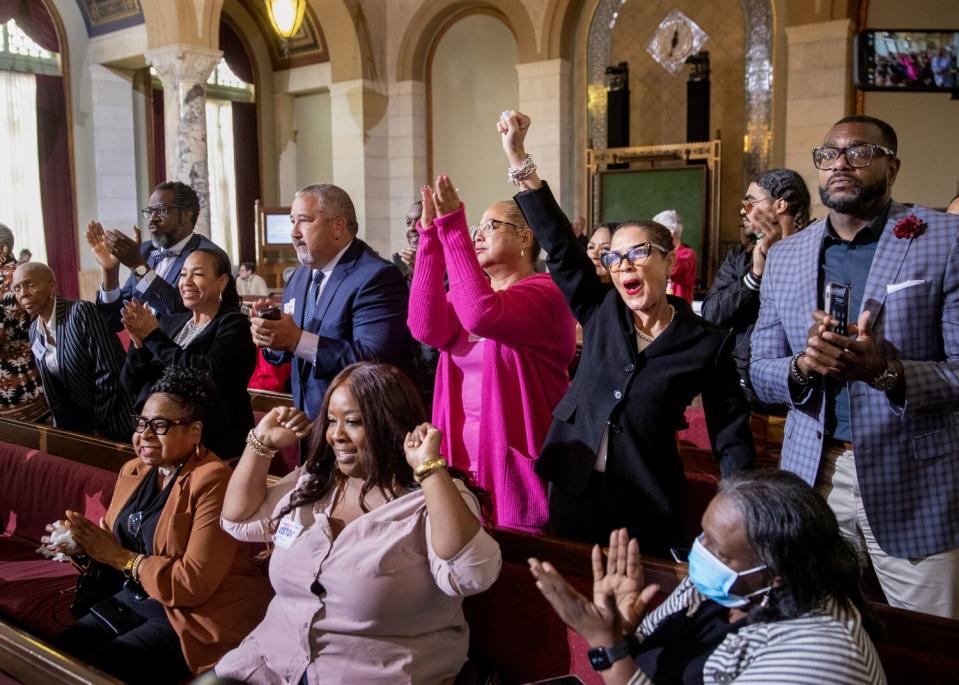 Supporters in the benches of a government hall cheer, some rising out of their seats