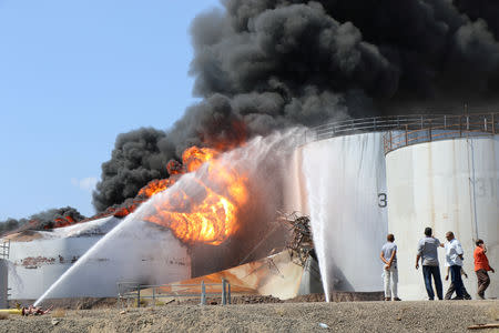 Workers look as fire engulfs an oil storage tank at the Aden oil refinery one day after an explosion in the refinery in Aden, Yemen January 12, 2019. REUTERS/Fawaz Salman