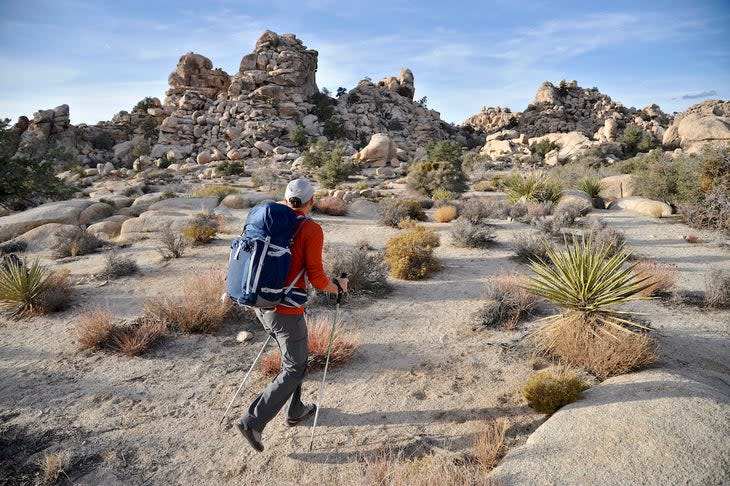 Backpacker hikes with trekking poles in Joshua Tree National Park.