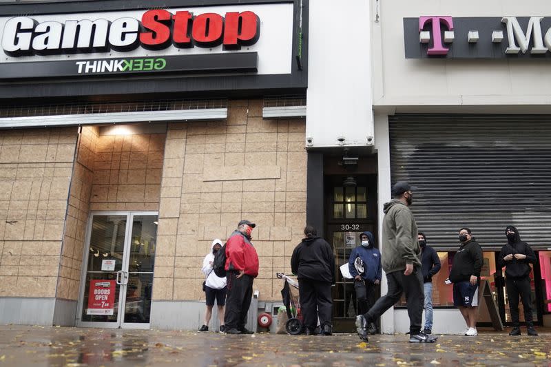 Outside a GameStop store people line up to purchase a Sony PS5 gaming console