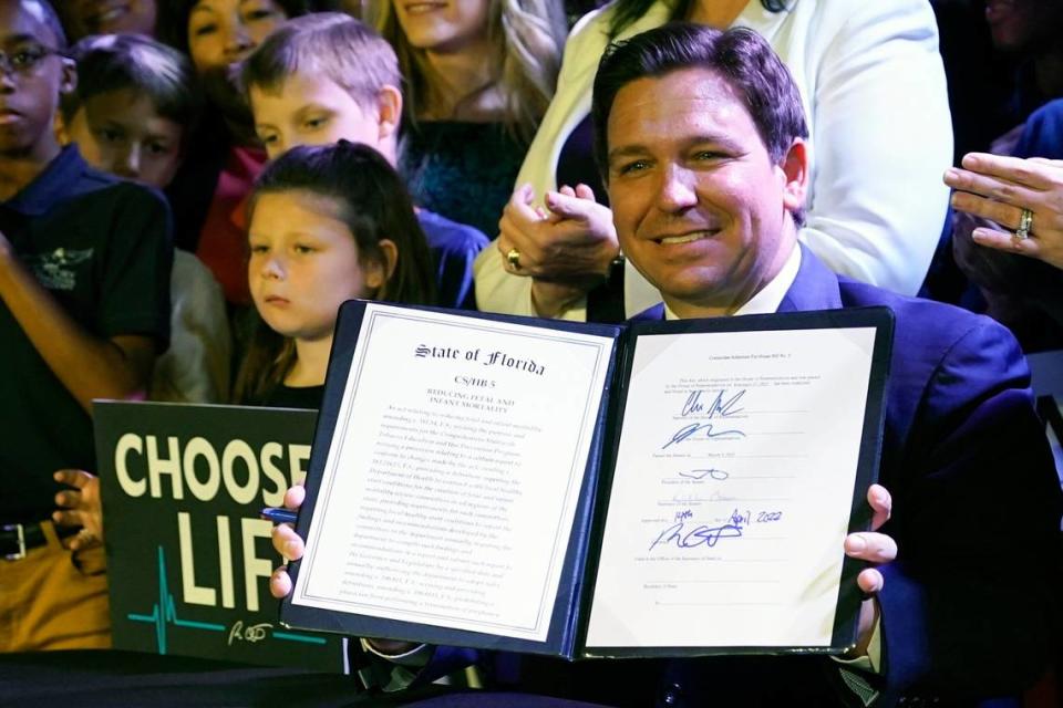 Florida Gov. Ron DeSantis holds up the legislation establishing a 15-week abortion ban after signing the measure on April 14, 2022, in Kissimmee, Florida. 