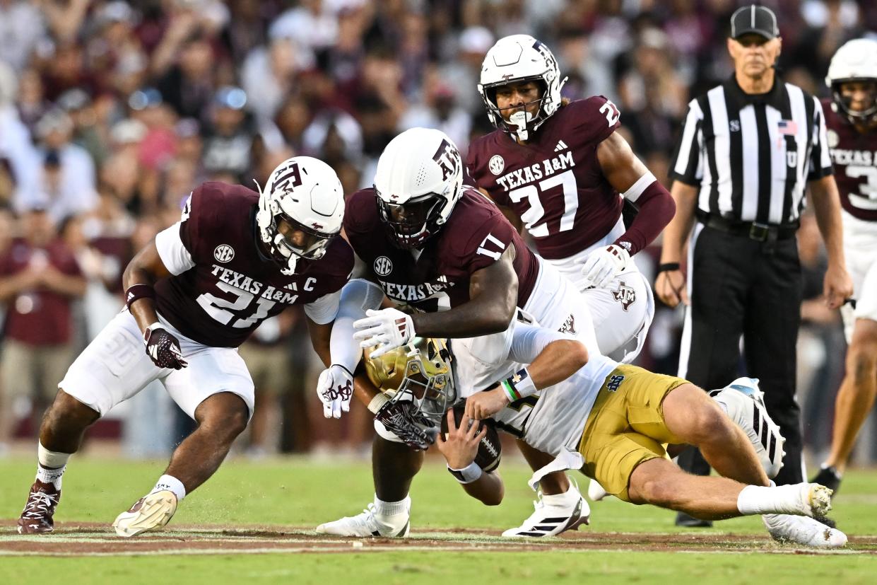 Texas A&M linebacker Taurean York, left and defensive lineman Albert Regis tackle Notre Dame quarterback Riley Leonard during the second quarter of Saturday night's season opener at Kyle Field.