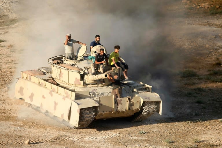 Rebel fighters ride a tank in Daraa, southwestern Syria, on June 23, 2018