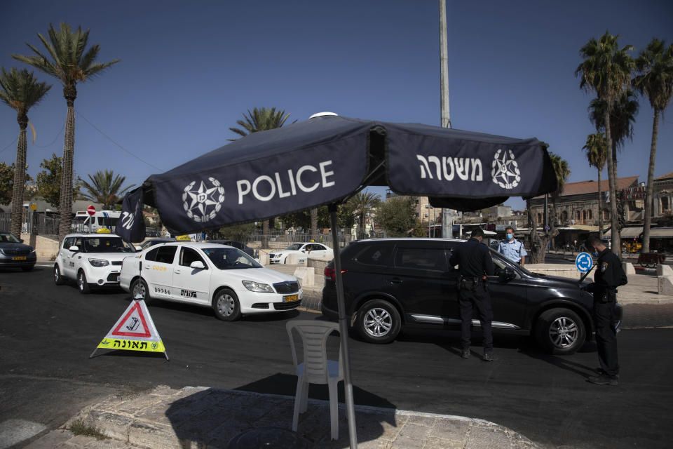Israeli police officers check cars during the current nationwide lockdown due to the coronavirus pandemic near the Damascus Gate in Jerusalem's old city, Tuesday, Sept. 29, 2020. (AP Photo/Sebastian Scheiner)