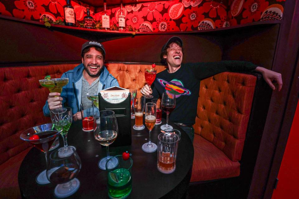 Tommy Wallach and Terry Pettigrew-Rolapp sitting around a small table with faux drinks on it.