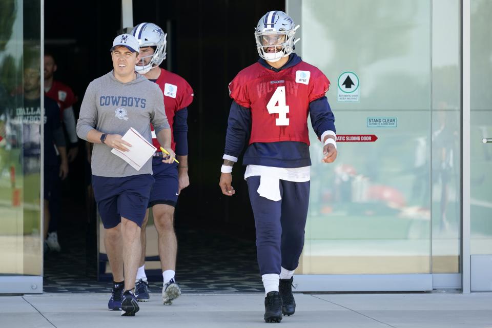 Dallas Cowboys quarterback Dak Prescott (4) walks onto the field followed by offensive coordinator Kellen Moore and practice squad quarterback Ben DiNucci (3) at the team's NFL football training facility in Frisco, Texas, Thursday, Sept. 23, 2021. (AP Photo/Tony Gutierrez)