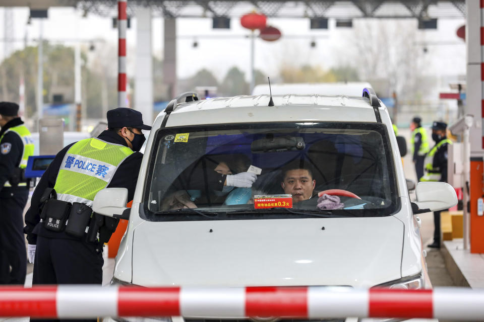 A policeman uses a digital thermometer to take a driver's temperature at a checkpoint at a highway toll gate in Wuhan in central China's Hubei Province, Thursday, Jan. 23, 2020. China closed off a city of more than 11 million people Thursday in an unprecedented effort to try to contain a deadly new viral illness that has sickened hundreds and spread to other cities and countries amid the Lunar New Year travel rush. (Chinatopix via AP)