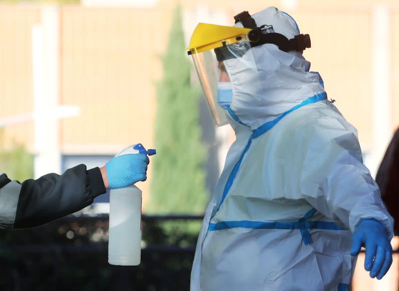 FILE PHOTO: An ambulance worker wearing a full personal protective equipment (PPE) is disinfected by a collage in Leganes