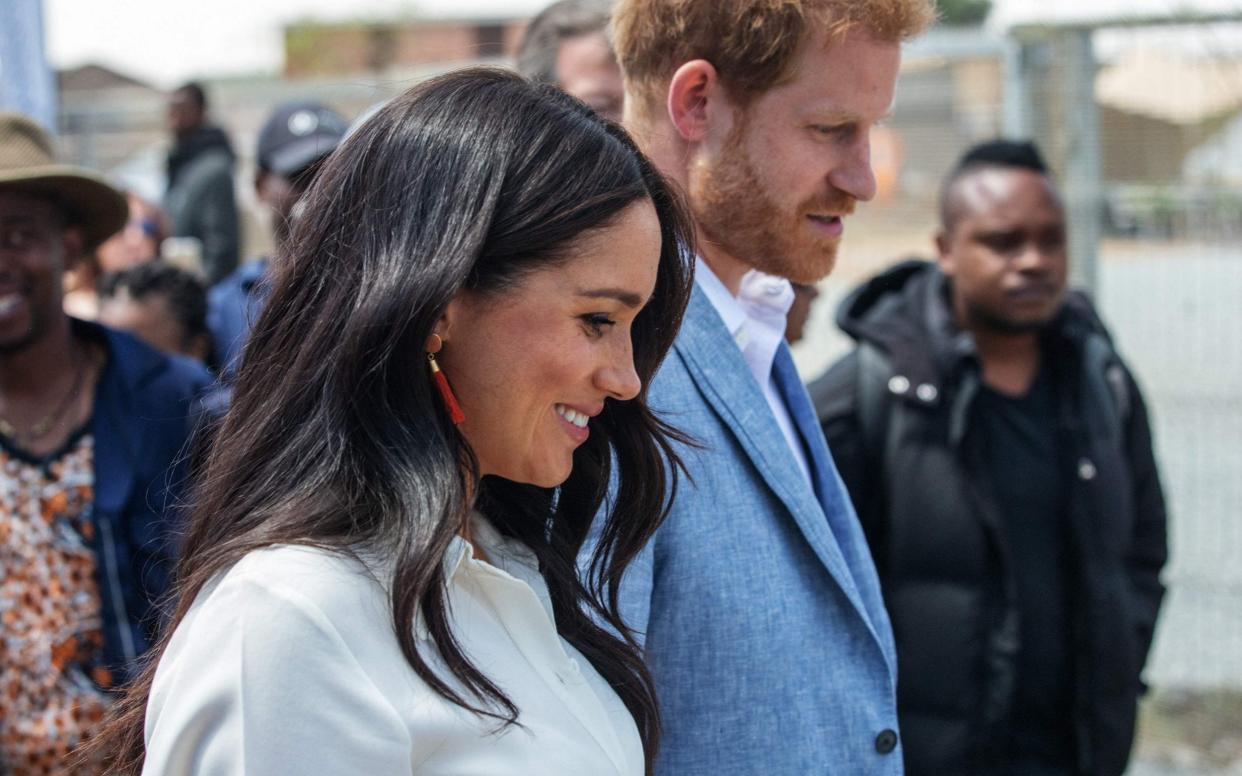 (FILES) In this file photo taken on October 02, 2019 Britain's Prince Harry, Duke of Sussex(R) and Meghan, Duchess of Sussex(L) leave the Youth Employment Services Hub in Tembisa township, Johannesburg. - Meghan Markle is to release a children's book titled 