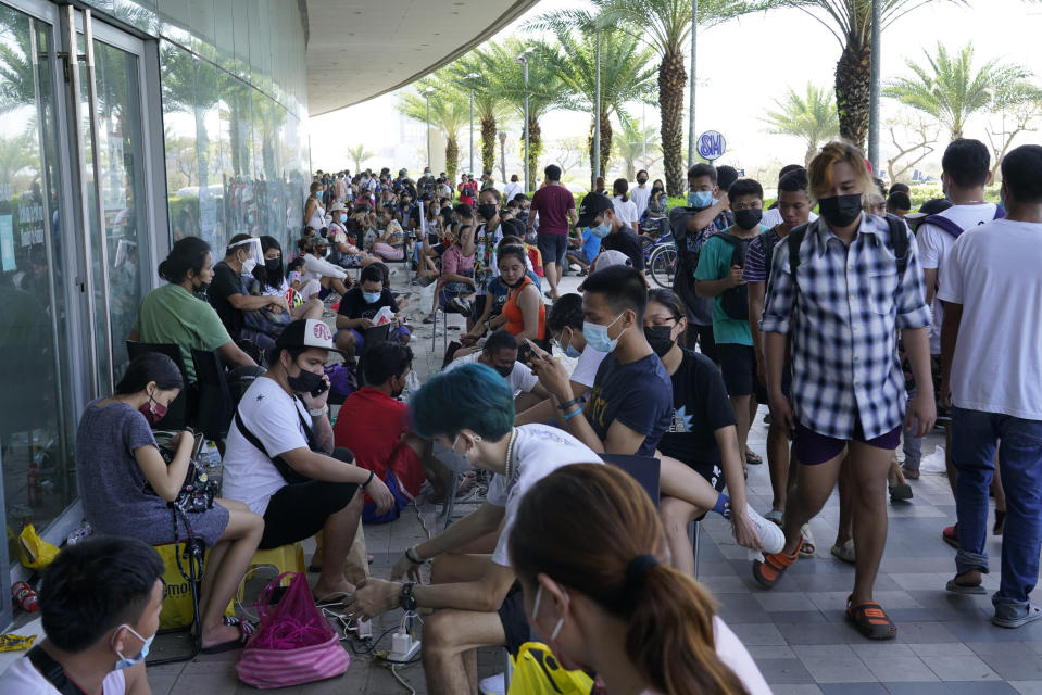 Residents line up to charge their phones for free at a mall after Typhoon Rai damaged power lines and other parts of Cebu city, central Philippines on Saturday, Dec. 18, 2021. A strong typhoon engulfed villages in floods that trapped residents on roofs, toppled trees and knocked out power in southern and central island provinces, where more than 300,000 villagers had fled to safety before the onslaught, officials said. (AP Photo/Jay Labra)