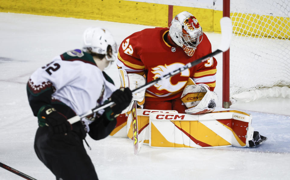 Calgary Flames goalie Dustin Wolf (32) stops a shot by Arizona Coyotes forward Logan Cooley (92) during the third period of an NHL hockey game in Calgary, Alberta, Sunday, April 14, 2024. (Jeff McIntosh/The Canadian Press via AP)