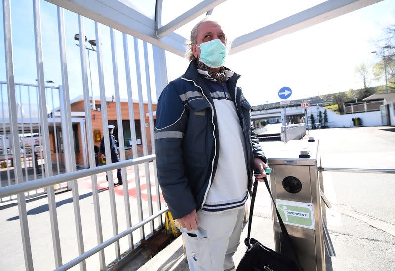 FILE PHOTO: Fiat Chrysler Automobiles (FCA) worker, wearing a protective face mask, leaves a Mirafiori plant, after the Italian government puts the whole country on lockdown as new coronavirus cases surge, in Turin