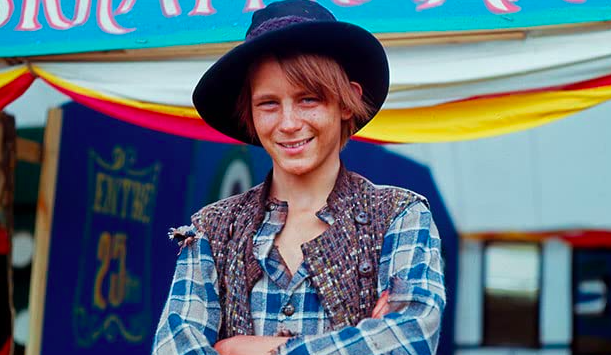 Photo of Stellan in "Bombi Bitt och jag," he wears a fedora-like cap, flannel button-down and multicolored vest