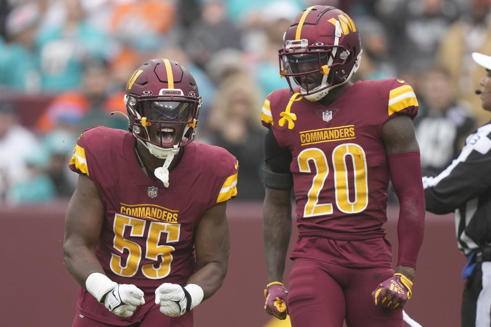 Washington Commanders defensive end KJ Henry (55) celebrates after a tackle next to safety Jartavius Martin (20) during the first half of an NFL football game against the Miami Dolphins Sunday, Dec. 3, 2023, in Landover, Md. (AP Photo/Mark Schiefelbein)