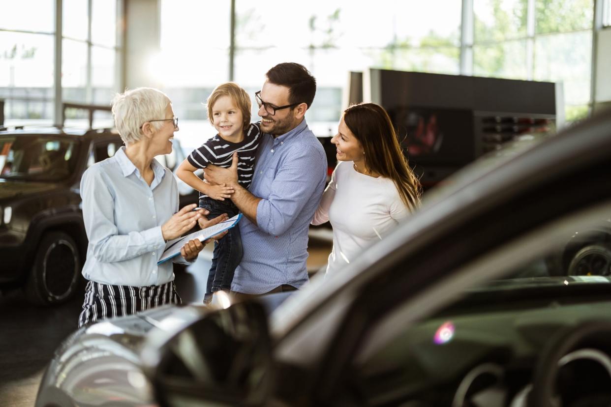 Young happy family talking to car salesperson in a showroom.