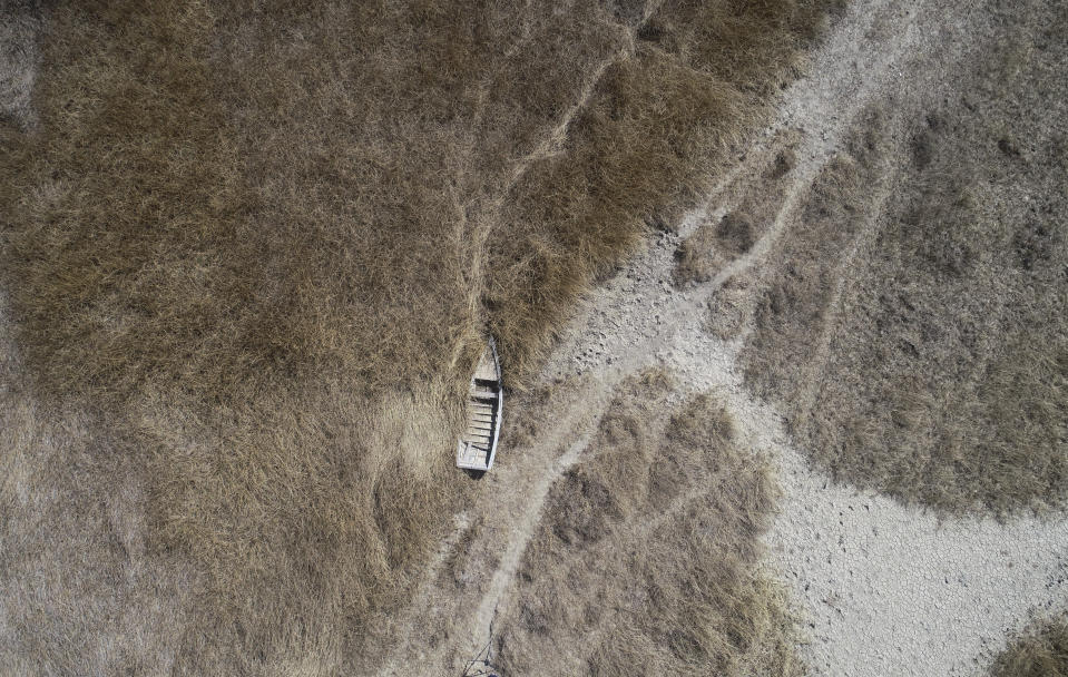 En la imagen, vista aérea de una embarcación abandonada cerca de la orilla del lago Titicaca, en Huarina, Bolivia, el 27 de julio de 2023. El bajo nivel del agua en el lago está teniendo un impacto directo en la flora y la fauna locales y afecta a las comunidades locales que dependen de la frontera natural entre Perú y Bolivia para su sustento. (AP Foto/Juan Karita)