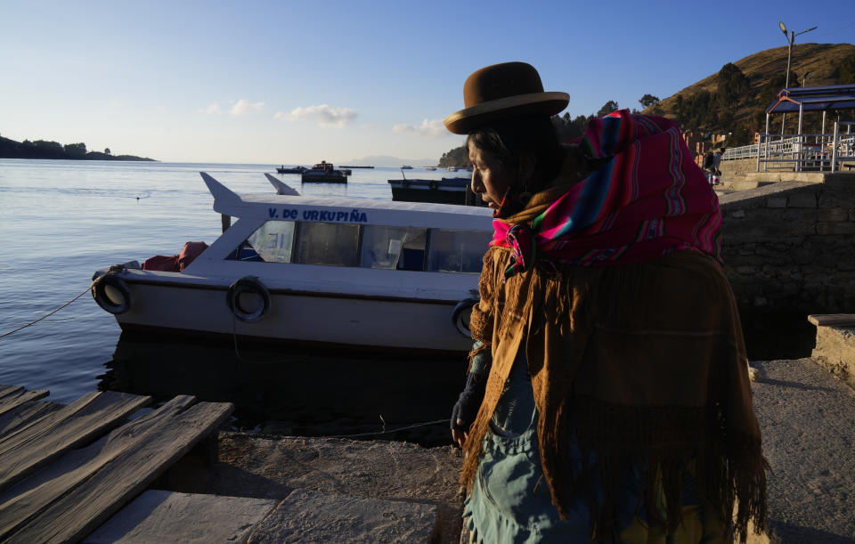 An Aymara woman walks alongside Lake Titicaca in the port of Tiquina, Bolivia, Thursday, July 27, 2023. The lake’s low water level is having a direct impact on the local flora and fauna and is affecting local communities that rely on the natural border between Peru and Bolivia for their livelihood. (AP Photo/Juan Karita)