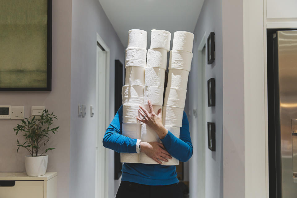 A person is holding a tower of toilet paper