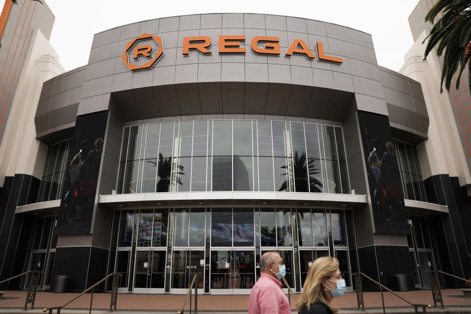 FILE - Two shoppers walk past a Regal movie theater in Irvine, Calif., on Sept. 8, 2020. Indoor movie theaters are open in most states, except New Mexico and Washington D.C., although some are on a county-by-county basis. Regal theaters are currently closed in the U.S, and independent cinemas vary by location, but AMC Theaters (the nation’s biggest chain) and Cinemark are largely up and running. Approximately 54% of screens are open in the U.S., according to the National Association of Theater Owners. (AP Photo/Jae C. Hong, File)