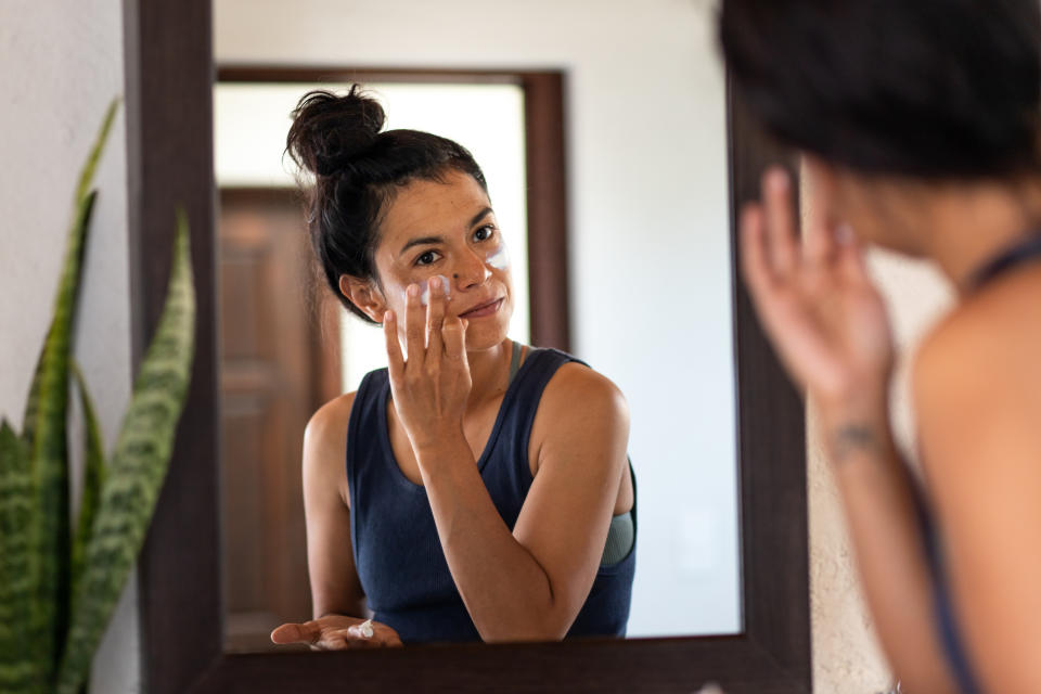 woman applying moisturizer on face