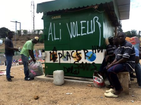 People sit next to graffiti that reads "Ali Thief", referring to incumbent President Ali Bongo, in Libreville, Gabon, September 24, 2016. Picture taken September 24, 2016. REUTERS/Marco Trujillo Henriquez