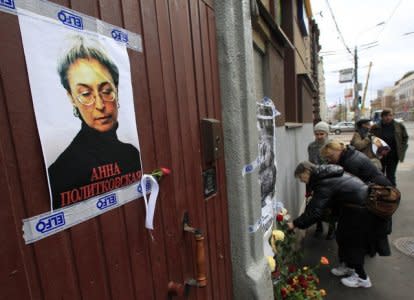 FILE PHOTO: People lay flowers next to a portrait of slain journalist Anna Politkovskaya on the sixth anniversary of her death, at her block of flats in central Moscow October 7, 2012. REUTERS/Sergei Karpukhin