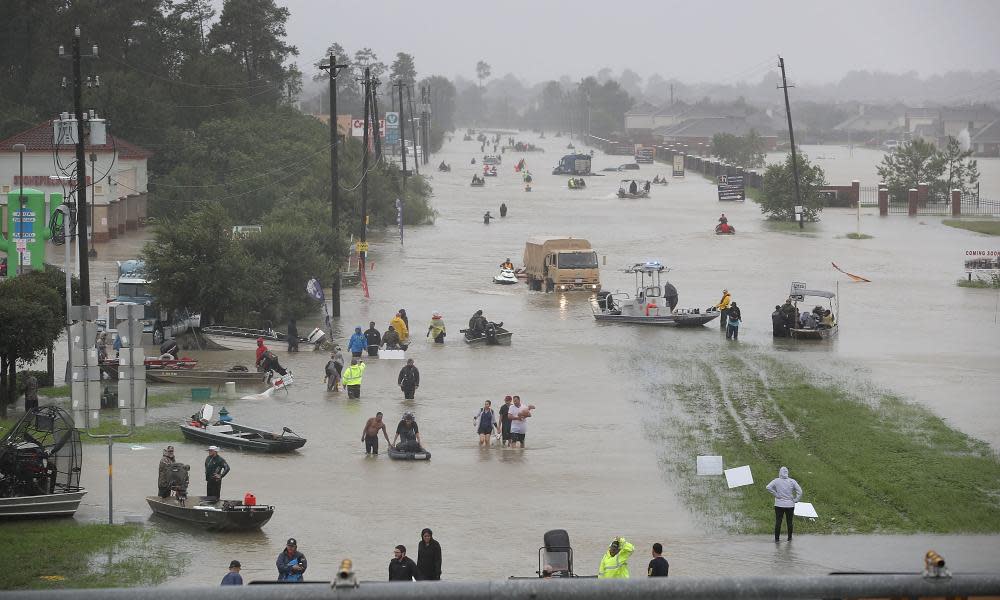 People walk down a flooded street as they evacuate their homes in Houston after Hurricane Harvey