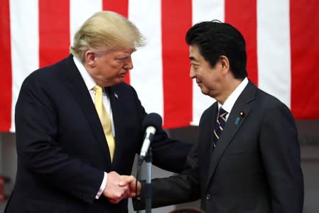 FILE PHOTO: U.S. President Donald Trump shakes hands with Japan's Prime Minister Shinzo Abe during delivering a speech to Japanese and U.S. troops as they aboard Japan Maritime Self-Defense Force's (JMSDF) helicopter carrier DDH-184 Kaga at JMSDF Yokosuka