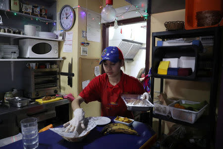 Fiamma, a Venezuelan worker in Spain, wears a cap in the national Venezuelan colours as she prepares food inside a Venezuelan traditional food restaurant in Madrid, Spain, May 16, 2018. REUTERS/Sergio Perez