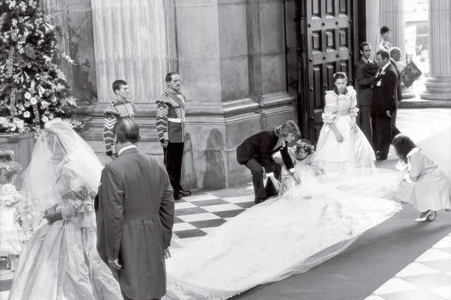 <p>Ted Blackbrow/Daily Mail/Shutterstock </p> Elizabeth Emanuel (right) helps straighten out Princess Diana's wedding dress on July 29, 1981