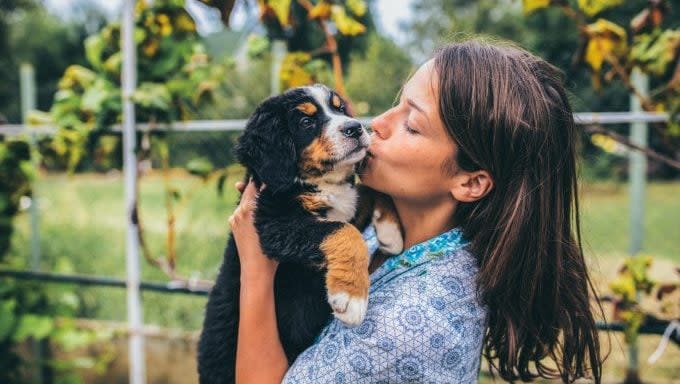 woman kissing puppy best and worst reasons to adopt a dog