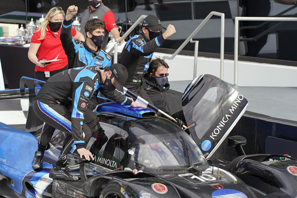 Filipe Albuquerque, of Portugal, drives the Acura DPi to Victory Lane as teammates Alexander Rossi, left, Ricky Taylor, Helio Castroneves, and team owner Wayne Taylor celebrate after winning the Rolex 24 hour auto race at Daytona International Speedway, Sunday, Jan. 31, 2021, in Daytona Beach, Fla. (AP Photo/John Raoux)