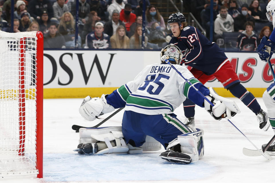 Columbus Blue Jackets' Adam Boqvist, top, prepares to shoot against Vancouver Canucks' Thatcher Demko during the second period of an NHL hockey game Friday, Nov. 26, 2021, in Columbus, Ohio. (AP Photo/Jay LaPrete)