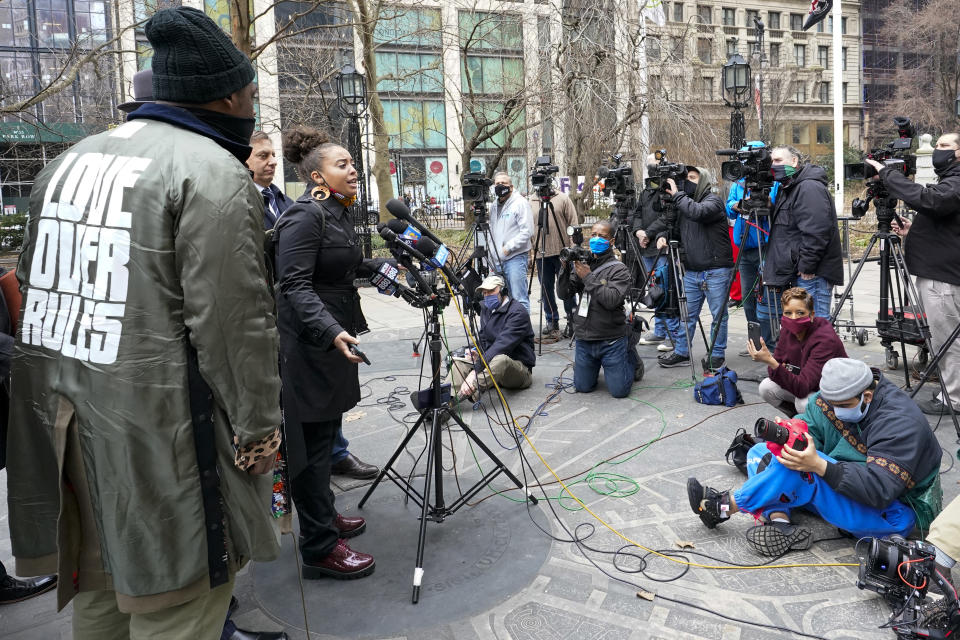 Keyon Harrold Sr., left, wears a jacket with the words "Love Over Rules" on the back as he listens to Katty Rodriguez, center, speak to reporters during a news conference to announce the filing of a lawsuit against Arlo Hotels and Miya Ponsetto, Wednesday, March 24, 2021, in New York. Keyon Harrold and his son were allegedly racially profiled in an Arlo hotel in Manhattan by Miya Ponsetto in December 2020. Ponsetto wrongly accused Keyon Harrold Jr. of stealing her phone and physically attacking him. (AP Photo/Mary Altaffer)