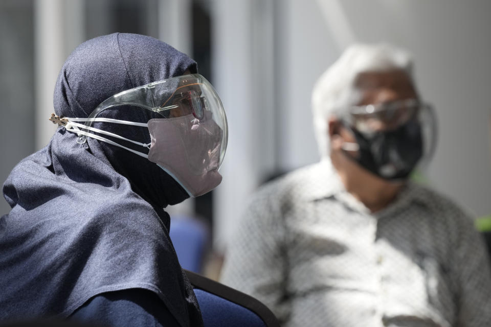 A Muslim couple wearing face mask and face shield while waiting for vaccine for the coronavirus disease (COVID-19) at a vaccination centre in Kuala Lumpur, Malaysia, Monday, May 31, 2021. An exhibition center in Malaysia has been turned into the country's first mega vaccination center as the government aims to speed up inoculations amid a sharp spike in infections. (AP Photo/Vincent Thian)