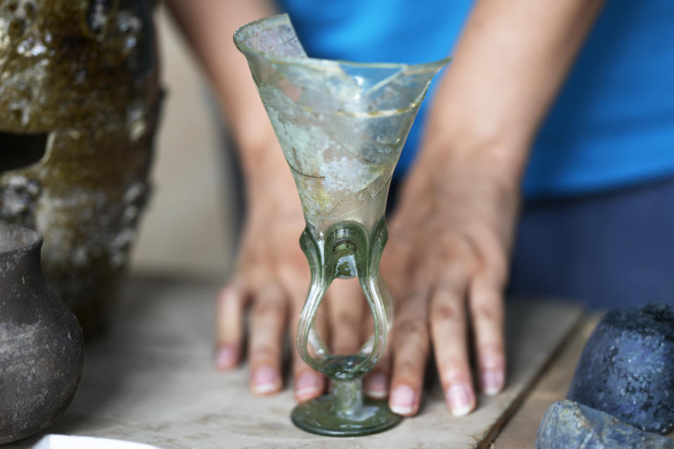 An archeologist shows a Medieval glass, dated to the 14th century A.D., coming from the excavation of Roman emperor Nero's theater, during a press preview, in Rome, Wednesday, July 26, 2023. The ruins of Nero's Theater, an imperial theater referred to ancient Roman texts but never found, have been discovered under the garden of the future Four Season's Hotel, steps from the Vatican, after excavating the walled garden of the Palazzo della Rovere since 2020, as part of planned renovations on the Renaissance building. (AP Photo/Andrew Medichini)