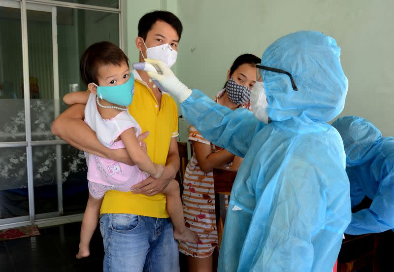 A health worker gets the temperature of residents at the area of a newly found coronavirus infected patient in Da Nang city