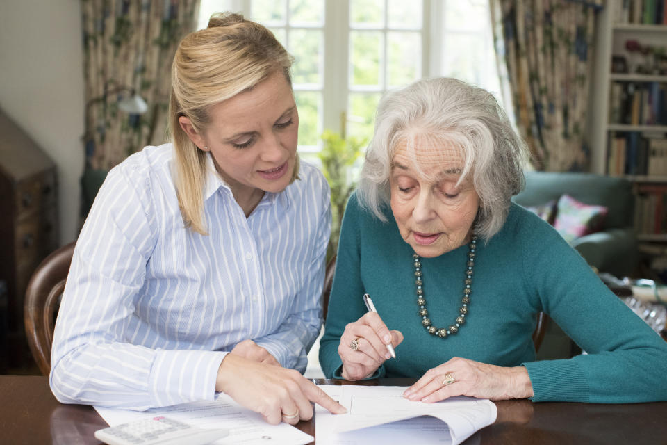 Parkinson's Woman Helping Senior Neighbor With Paperwork