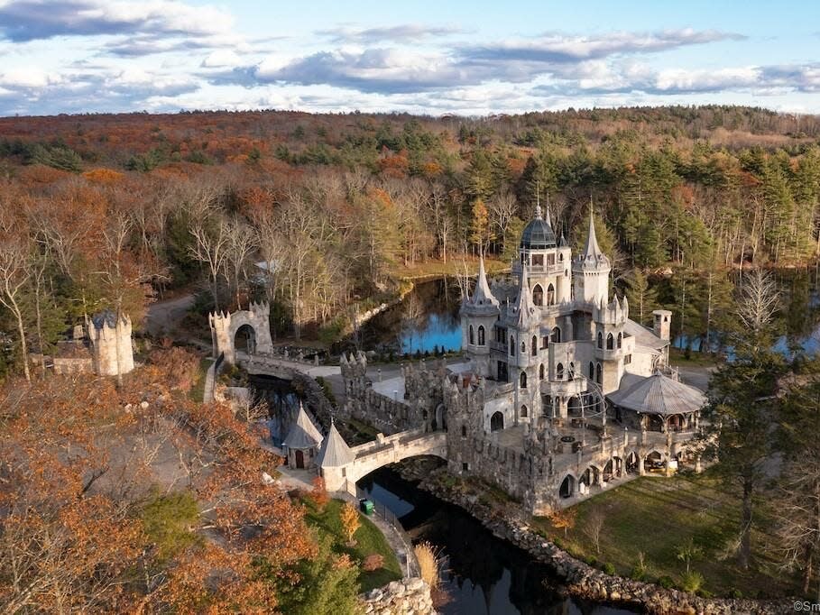 a castle with a moat and towers surrounded by water and trees in autumn in Connecticut