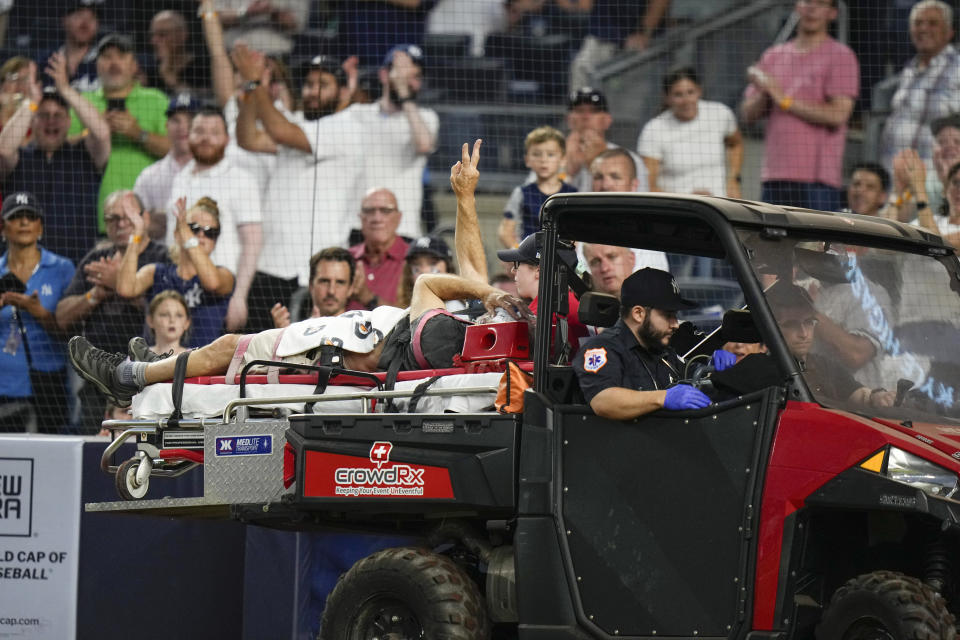 A camera operator who was injured on a throwing error by Baltimore Orioles third baseman Gunnar Henderson gestures to the crowd as he is carted off the field during the fifth inning of the Orioles' baseball game against the New York Yankees on Wednesday, July 5, 2023, in New York. (AP Photo/Frank Franklin II)