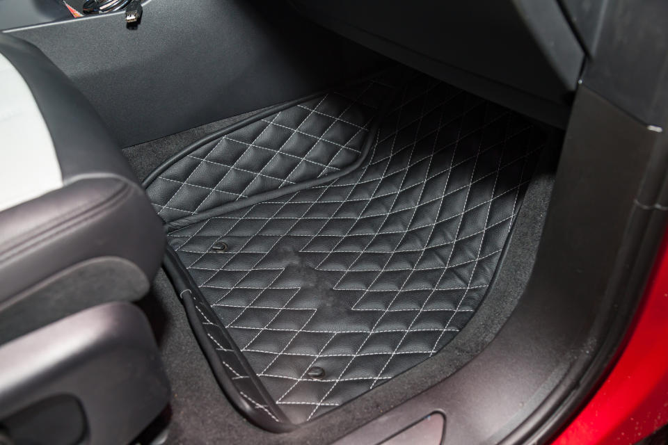 A close-up of a car's footwell with quilted floor mats