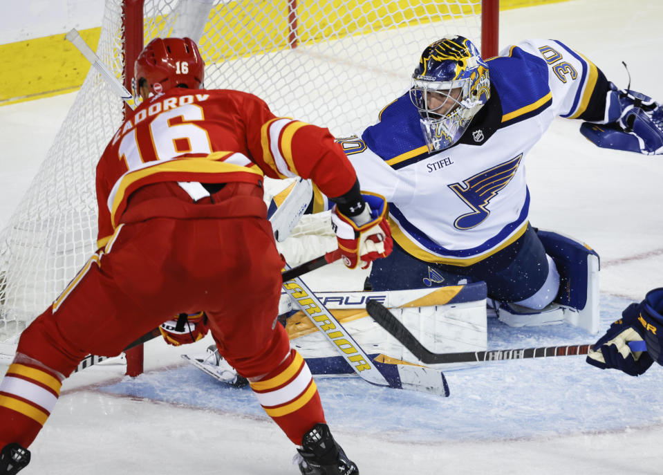 St. Louis Blues goalie Joel Hofer (30) blocks a shot by Calgary Flames defenseman Nikita Zadorov, left, during third-period NHL hockey game action in Calgary, Alberta, Thursday, Oct. 26, 2023. (Jeff McIntosh/The Canadian Press via AP)