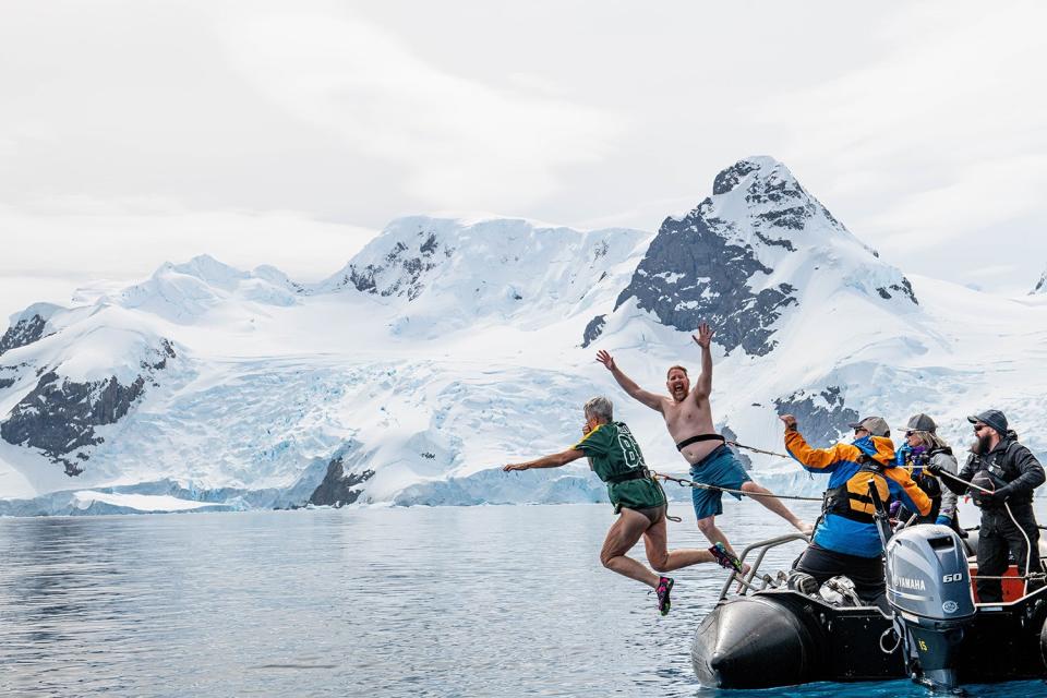 two tourists leap from a boat into the antarctic water