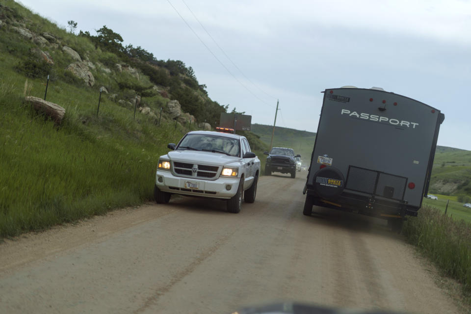 A escort vehicle guides traffic through a single-lane county road after a key bridge that leads to the tourist town of Fishtail, Mont., collapsed, causing traffic to divert, Friday, June 17, 2022. (AP Photo/David Goldman)