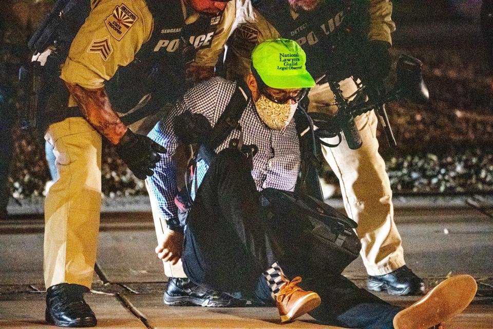 Arizona State Troopers detain Russell Facente, a legal observer with the National Lawyers Guild after protesters pulled down a gate around the perimeter of the Arizona Capitol in Phoenix on June 25, 2022, during an abortion-rights protest following the Supreme Court's decision to overturn Roe v. Wade. At least a dozen protesters were arrested.