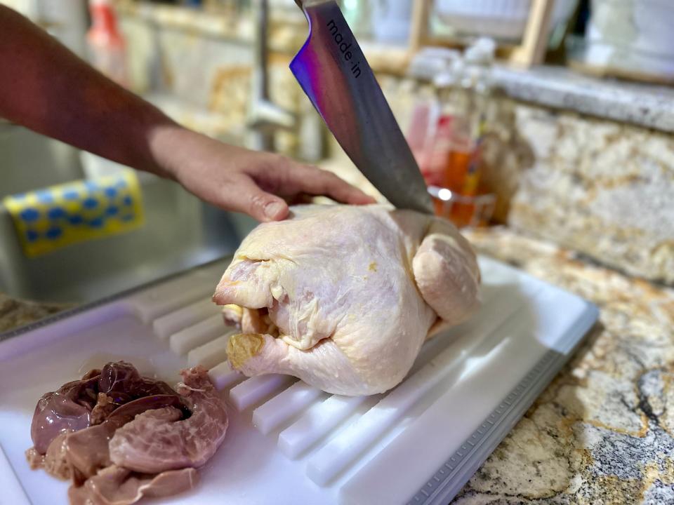 terri cutting a whole chicken into pieces on a cutting board