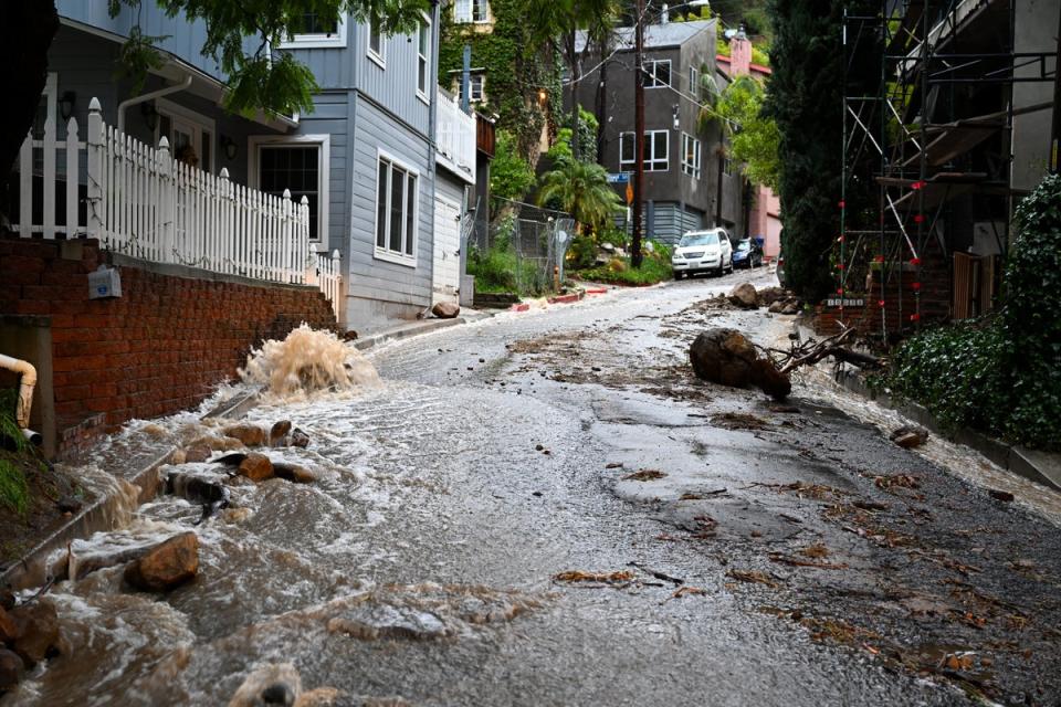 Floodwaters rush down a street in Los Angeles’ Beverly Crest neighbourhood on Monday (Anadolu via Getty Images)