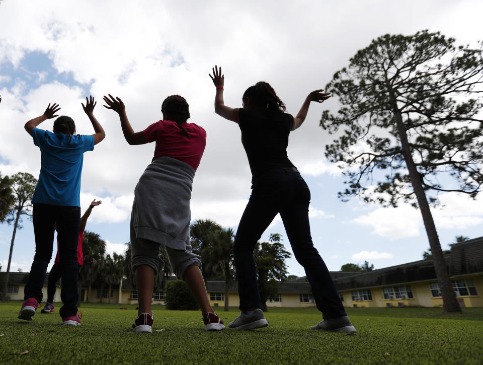 FILE - In this Sept. 24, 2019, file photo, girls dance as they do exercises at a shelter for migrant teenage girls, in Lake Worth, Fla. The nonprofit U.S. Committee for Refugees and Immigrants opened the federally funded Rinconcito del Sol shelter this summer, aiming to make it a model of excellence in a system of 170 detention centers, residential shelters and foster programs which held nearly 70,000 migrant kids in the past year. (AP Photo/Wilfredo Lee, File)