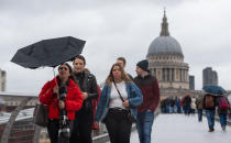 A woman struggles with an umbrella in strong winds on the Millennium Bridge in central London. (Getty)