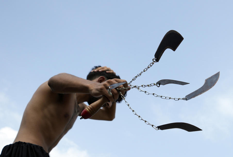 A Shiite Muslim flagellates himself with knifes on chains during a procession to mark Ashoura, in Islamabad, Pakistan, Friday, July 28, 2023. Ashoura is the Shiite Muslim commemoration marking the death of Hussein, the grandson of the Prophet Muhammad, at the Battle of Karbala in present-day Iraq in the 7th century.(AP Photo/Rahmat Gul)